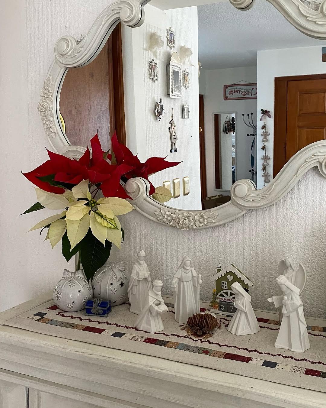 Nochebuena roja y blanca junto a un espejo y un nacimiento